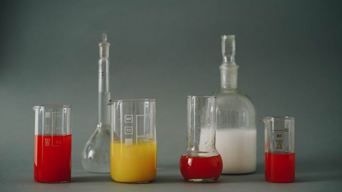 Studio shot of colorful laboratory beakers and glassware on gray backdrop.