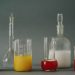 Studio shot of colorful laboratory beakers and glassware on gray backdrop.